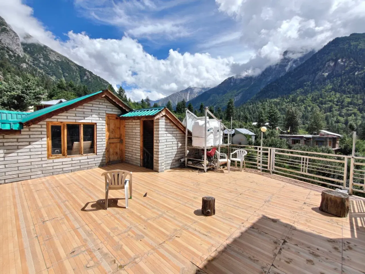 The lodge's wooden sun deck facing the forested walls of the Sangla valley